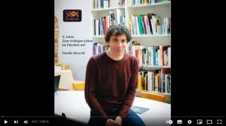 Davide Brocchi in einer Bibliothek mit dem Logo der Veranstaltungsreihe
